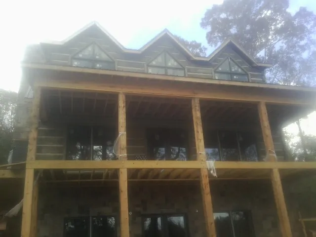Dormers and porch framing on a large log home under construction — Roof Coating work by our crew in Nunda